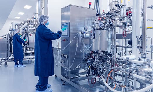 gowned cleanroom operator carrying cell culture vessel